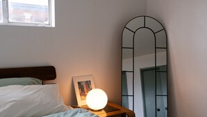 Une chambre à coucher avec un lit, une table de chevet avec une lampe et un miroir.
