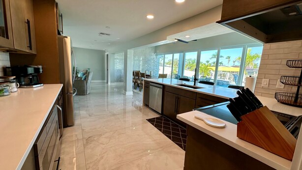 A modern kitchen with a large island, built-in appliances, and a view of the outdoors. - Sea U Soon - Luxury Dock Home (Fort Myers Beach)