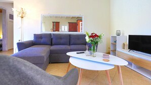 A living room with a grey sofa, a white coffee table, a flat-screen TV, and a mirror reflecting the room. - Villa Serenita in Agios Georgios (Corfu)