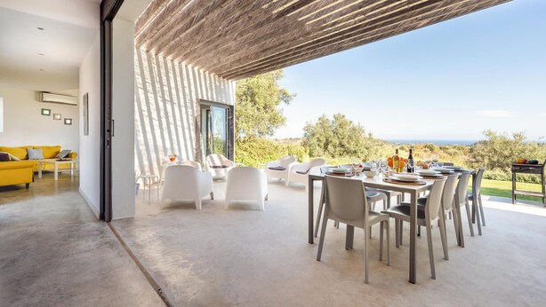 A modern interior with a dining area overlooking a scenic landscape. - Villa Il Cavaliere Dependance by Elite Villas (Noto)