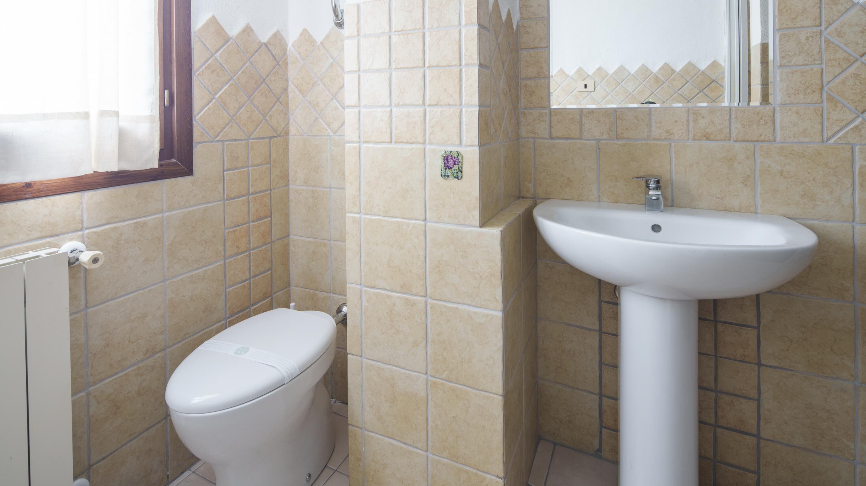 A bathroom with a toilet, a sink, and tiled walls.