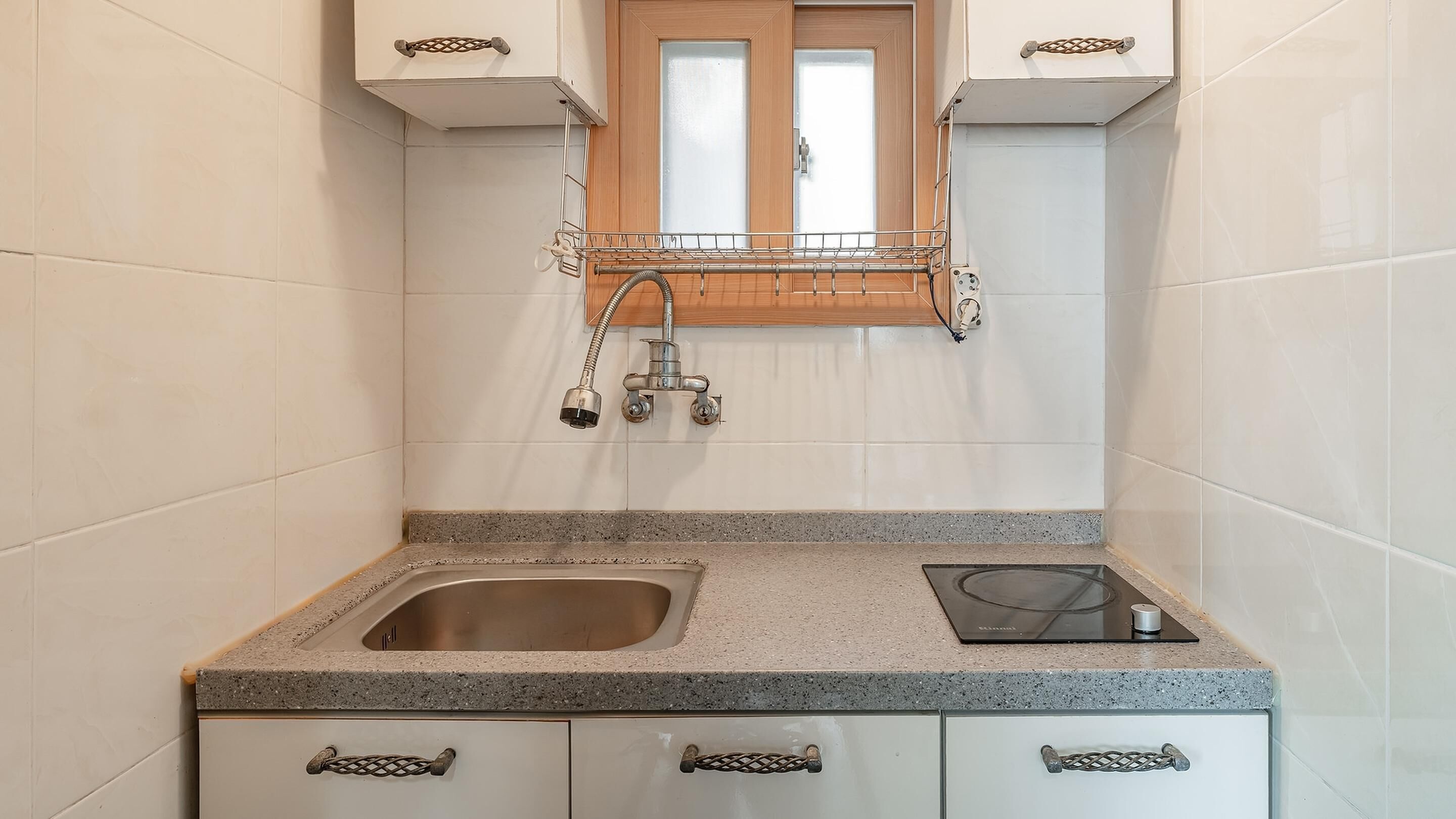 Una cocina compacta con un lavamanos doble, una estufa empotrada y una ventana sobre el lavamanos.