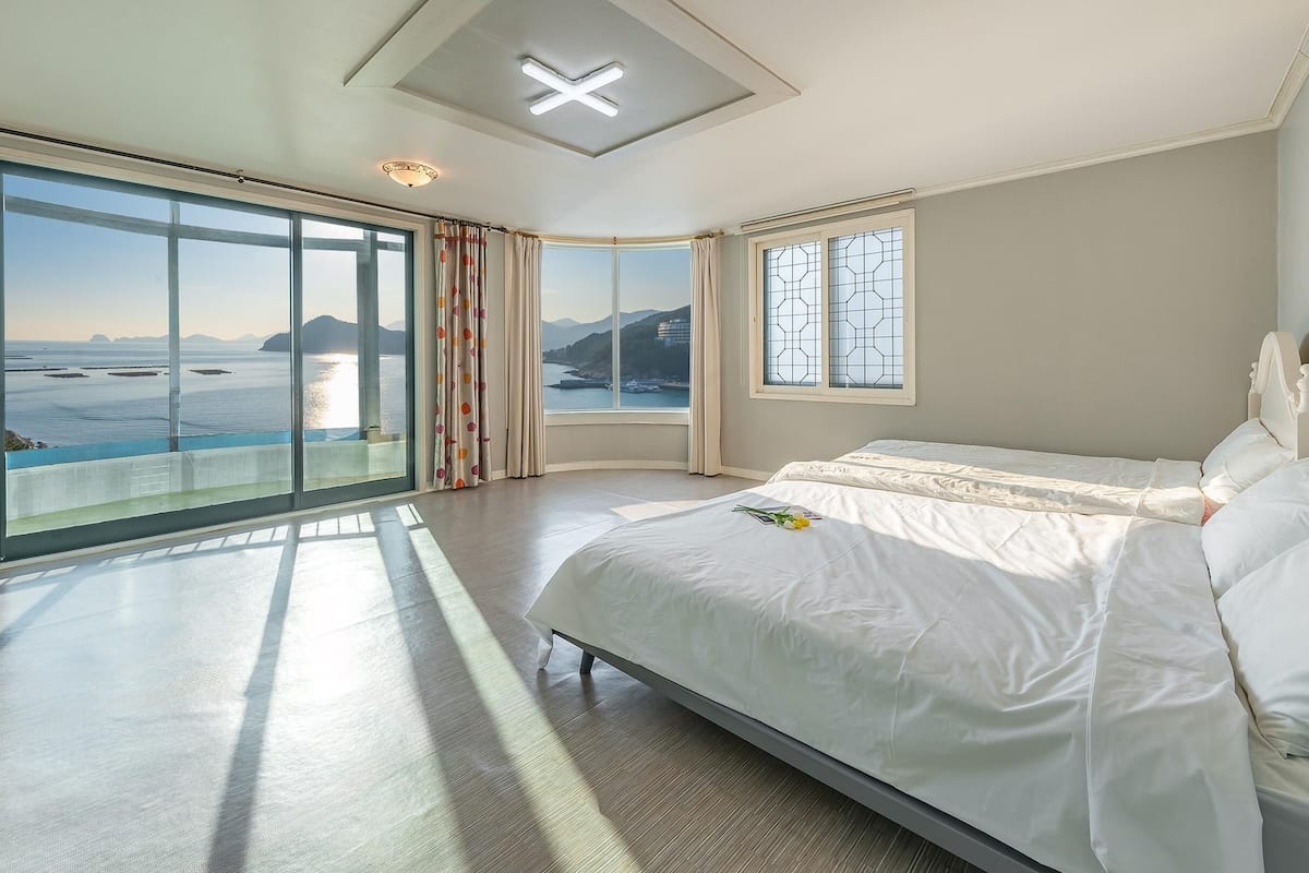 A spacious bedroom with a large bed, a view of the sea, and a skylight.