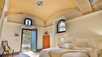 Un dormitorio con cama, una silla, un armario de madera y una puerta que da al exterior.