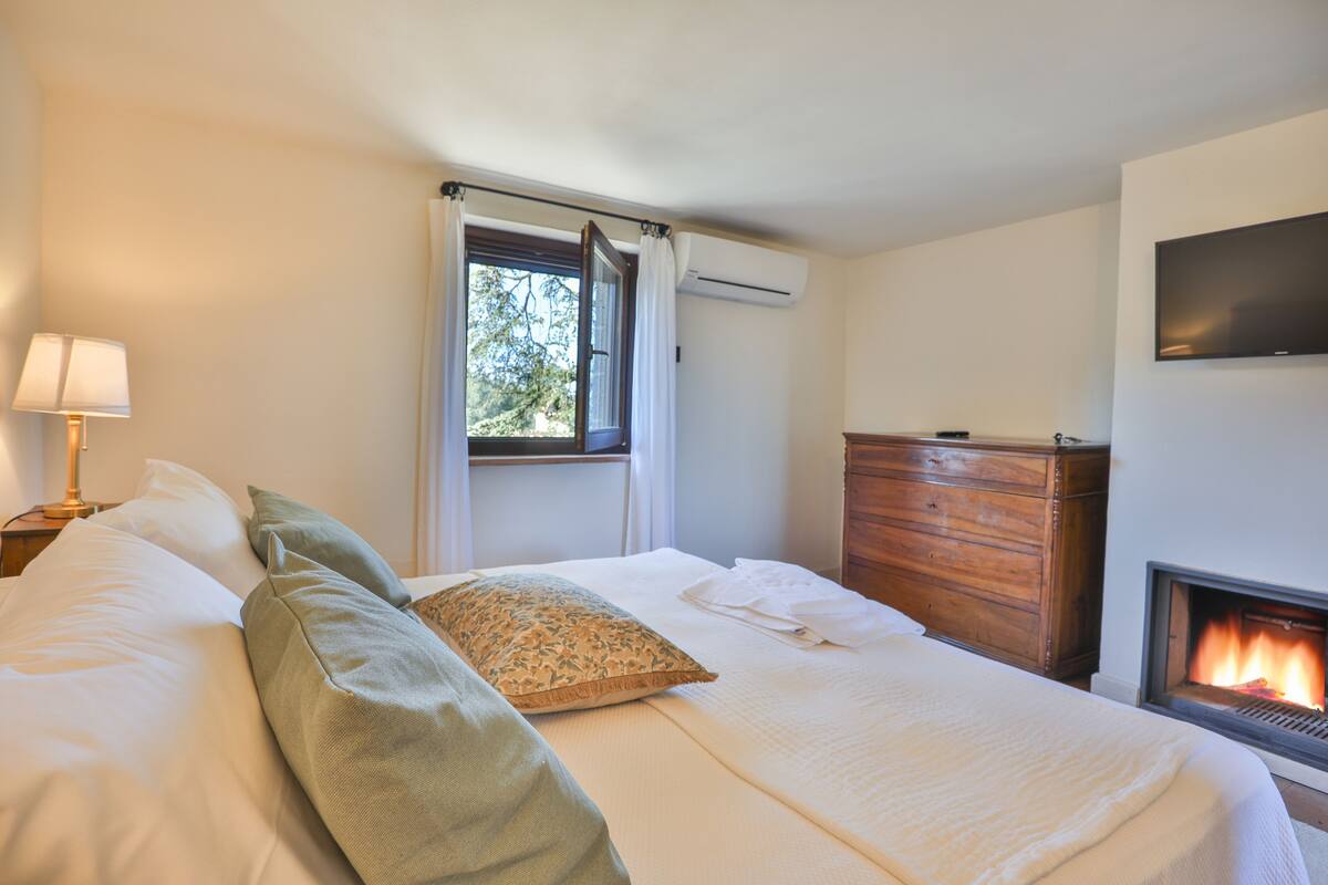 Un dormitorio con cama, cómoda, chimenea y equipo de aire acondicionado.