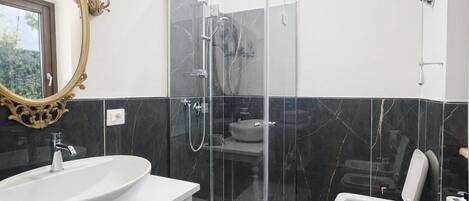 A modern bathroom with a glass-enclosed shower, a white sink, and a toilet.
