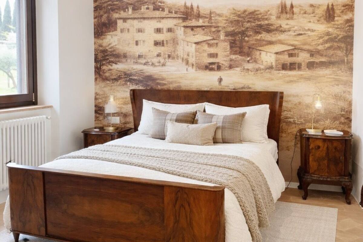Un dormitorio con una cama de madera, un mural grande en la pared, una ventana y dos mesitas de noche con lámparas.