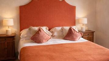 Un dormitorio con una cama grande, cabecera de madera, dos mesitas de noche con lámparas y techo de madera.