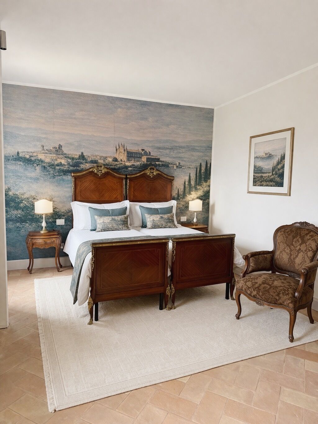 A bedroom with a large bed, two bedside tables, a chair, a large painting on the wall, and a view of a landscape.
