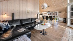 Un salon moderne avec un canapé en cuir, une table basse ronde blanche et des murs recouverts de panneaux en bois.