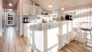Une cuisine moderne avec des meubles blancs, un îlot central et des luminaires suspendus.