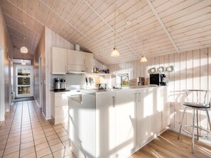 Een koelkast, een vaatwasser, kookgerei, borden en bestek