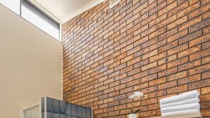 A bathroom with a bathtub, a shower enclosure, and a brick wall.