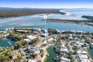 An aerial view of a coastal town with residential buildings, a marina, and a large body of water.