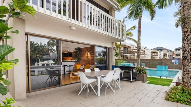 A modern outdoor patio with a dining table and chairs, a barbecue grill, and a swimming pool.