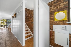 Una escalera conduce a un segundo piso con una pared de ladrillo y una puerta blanca.