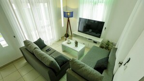 A living room with a sofa, a coffee table, a TV, and a lamp.