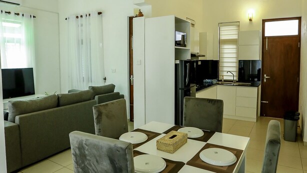 A modern living room with a dining area, kitchen, and a large window.