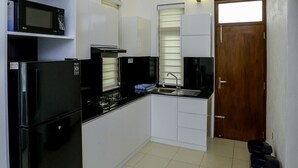 A modern kitchen with white cabinets, black appliances, and a wooden ceiling.