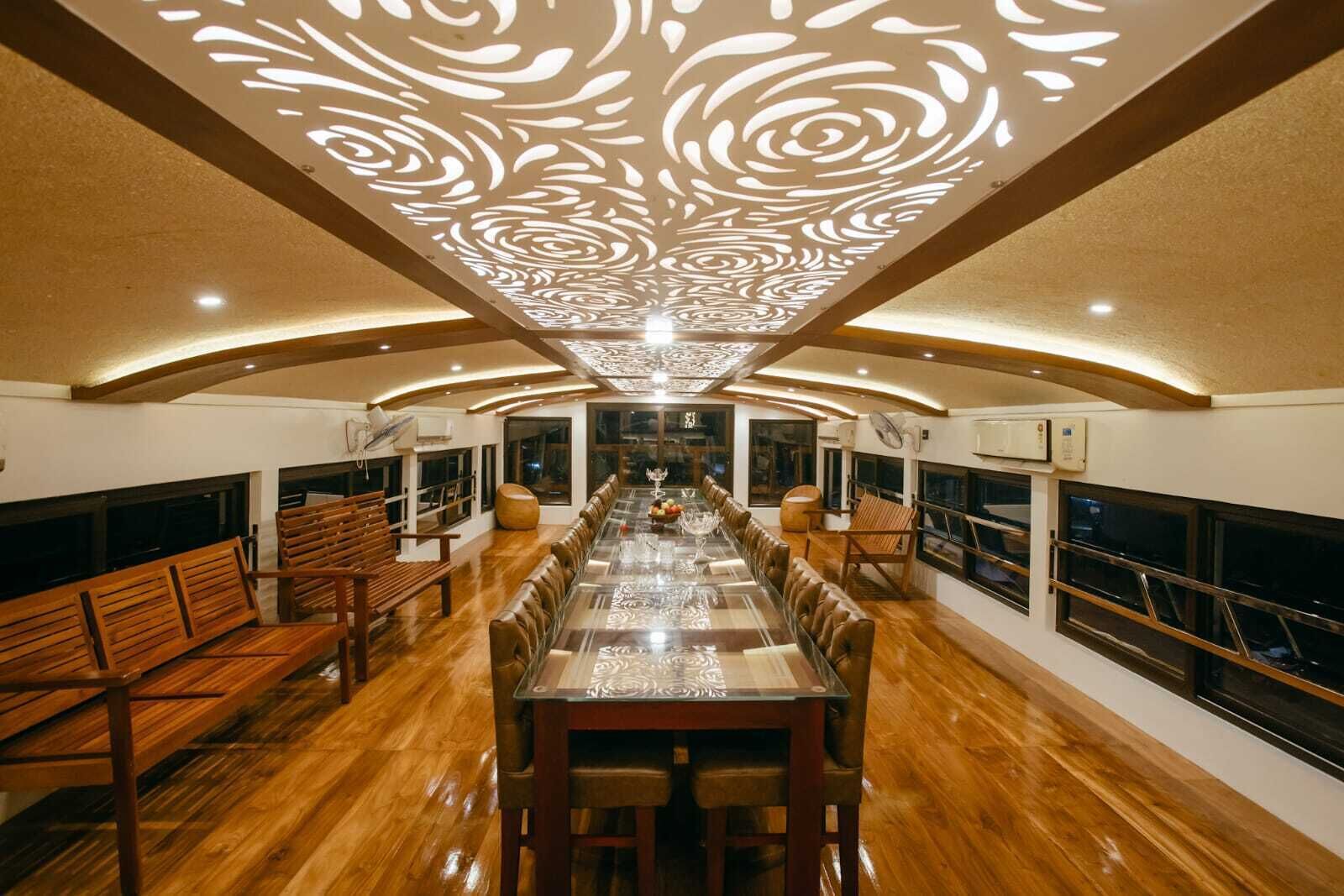 A long dining table with chairs, wooden benches, and a patterned ceiling.