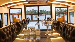Un espace repas avec des banquettes en cuir, une table en verre et une vue sur l’eau.