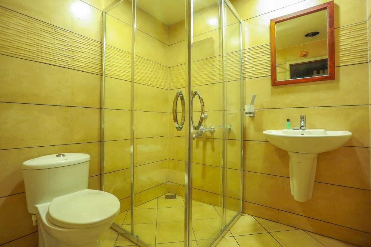 Une salle de bain avec une douche à parois de verre, un lavabo blanc et des toilettes.