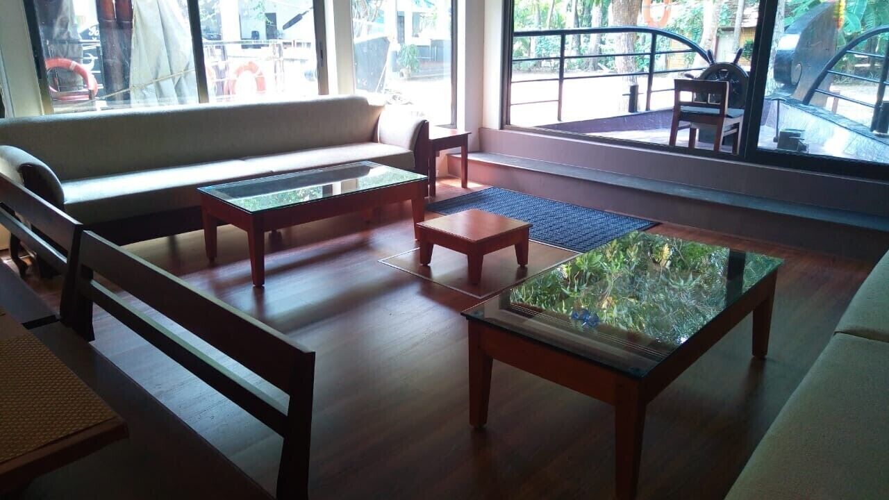 A spacious living area with a sofa, two wooden coffee tables, and a glass-top table with a decorative item.