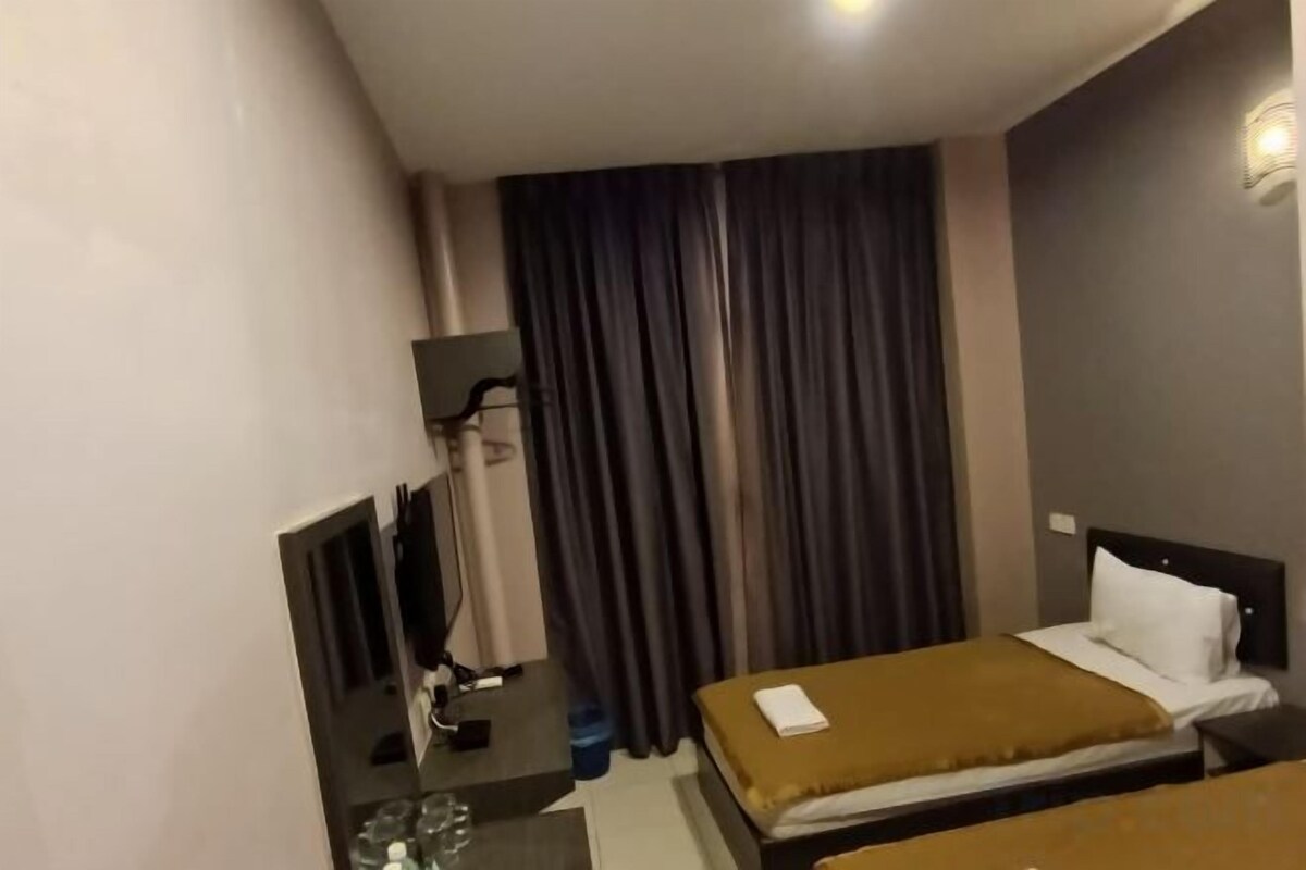 A hotel room with a bed, a desk with a computer, and a window with curtains.