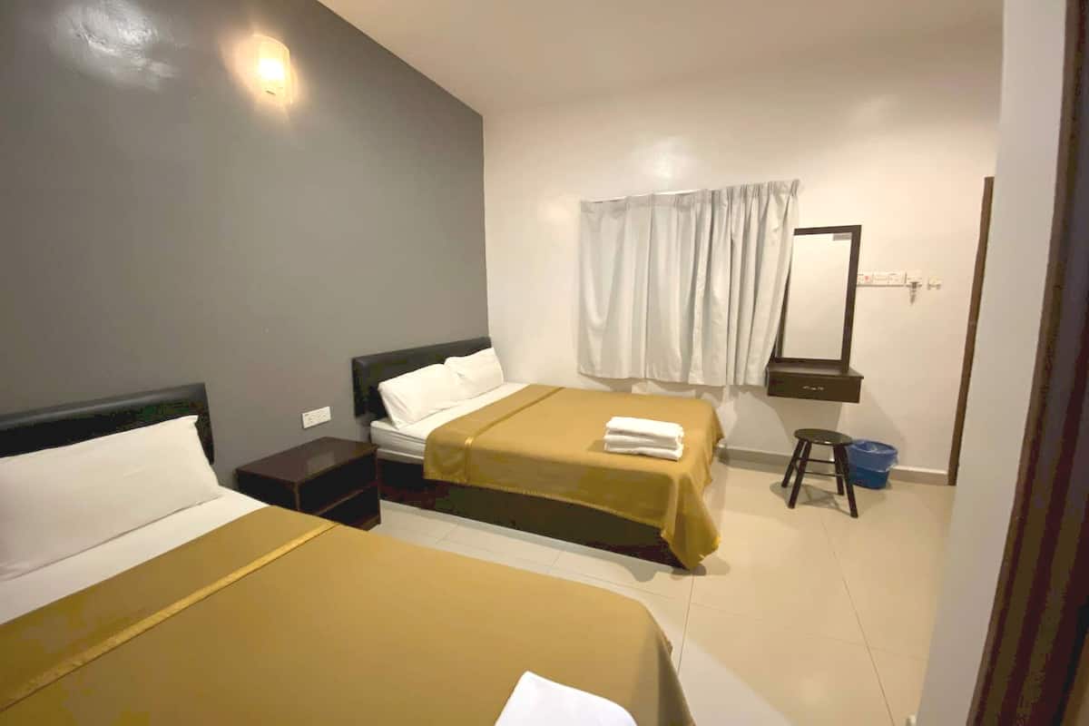 A hotel room with two beds, a nightstand, a mirror, and a small stool.