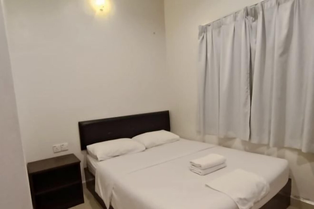 A single bed with white linens, a dark headboard, and a bedside table.