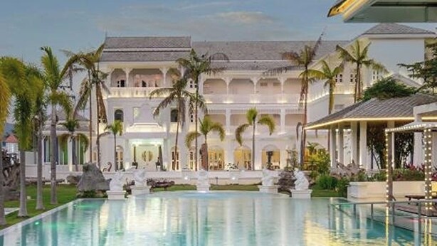 A large pool with a reflection, a building with multiple balconies, and palm trees. - Lanna Inthan Hotel & Resort (Doi Saket)