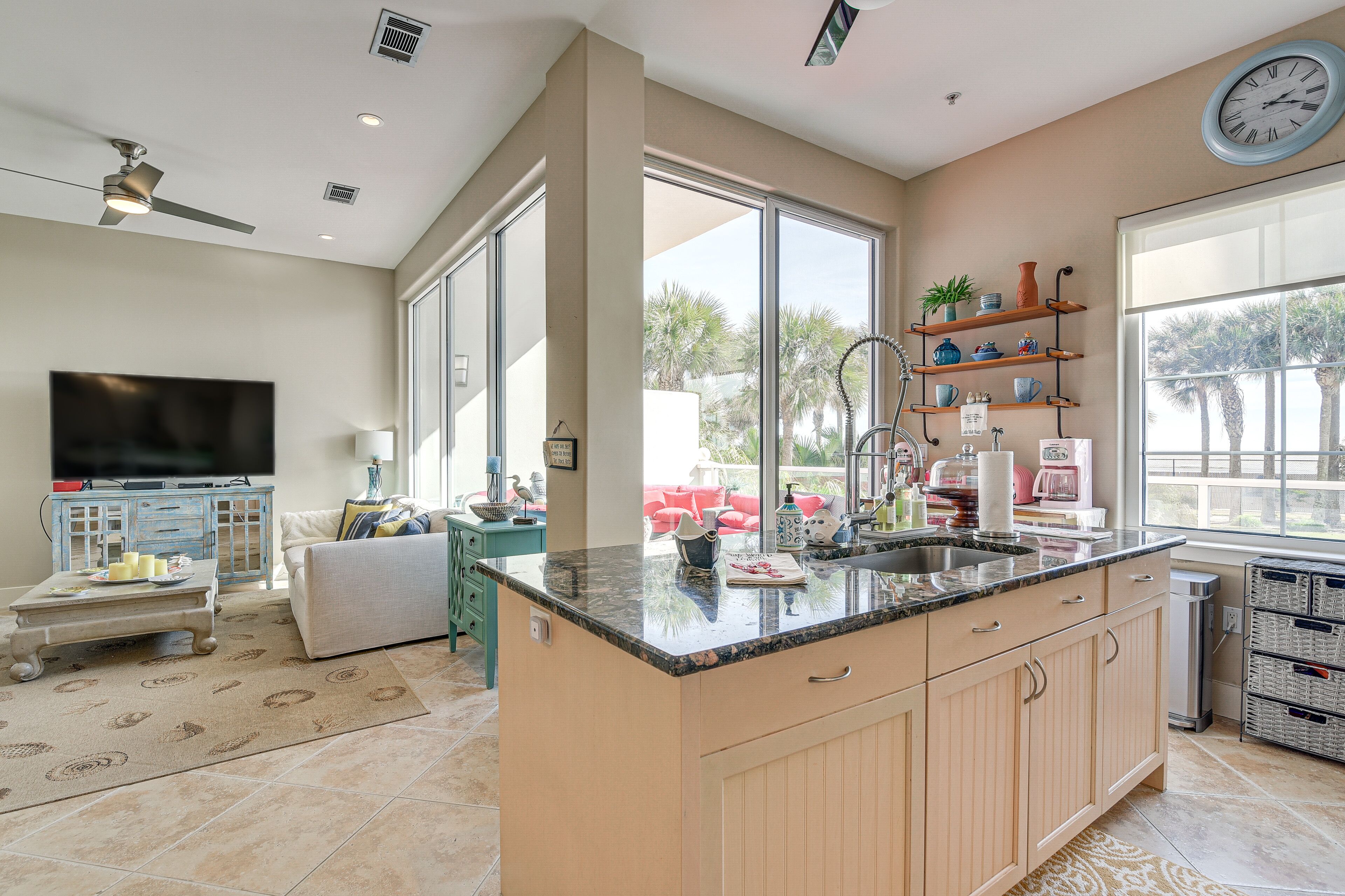 A modern kitchen with a large island, a dining area with a sofa, and a TV in the living room.