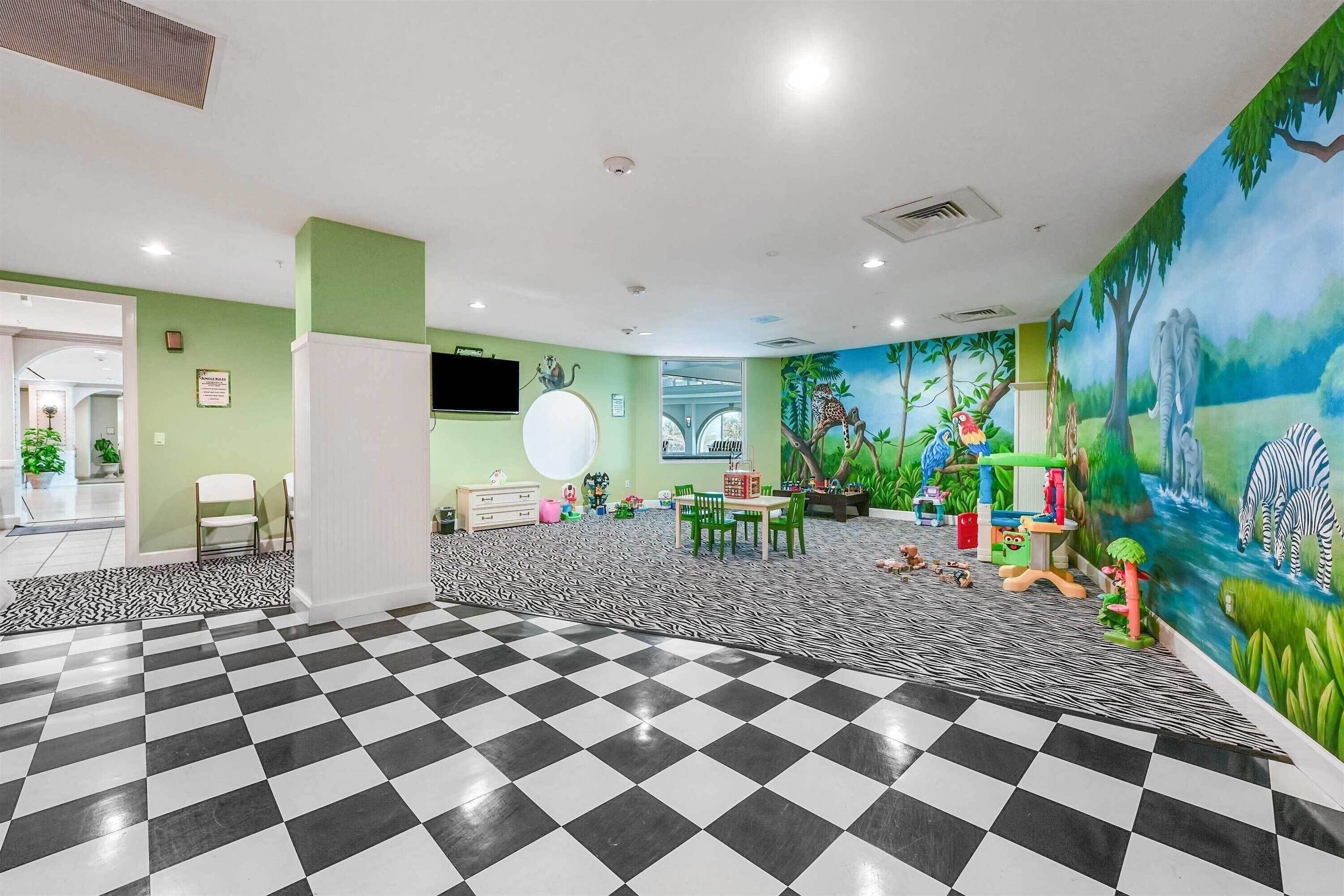 A children's play area with a checkered floor, green walls, and a mural of animals.