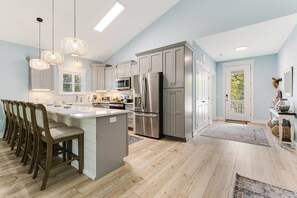A modern kitchen with a central island, stainless steel appliances, and a light blue wall.