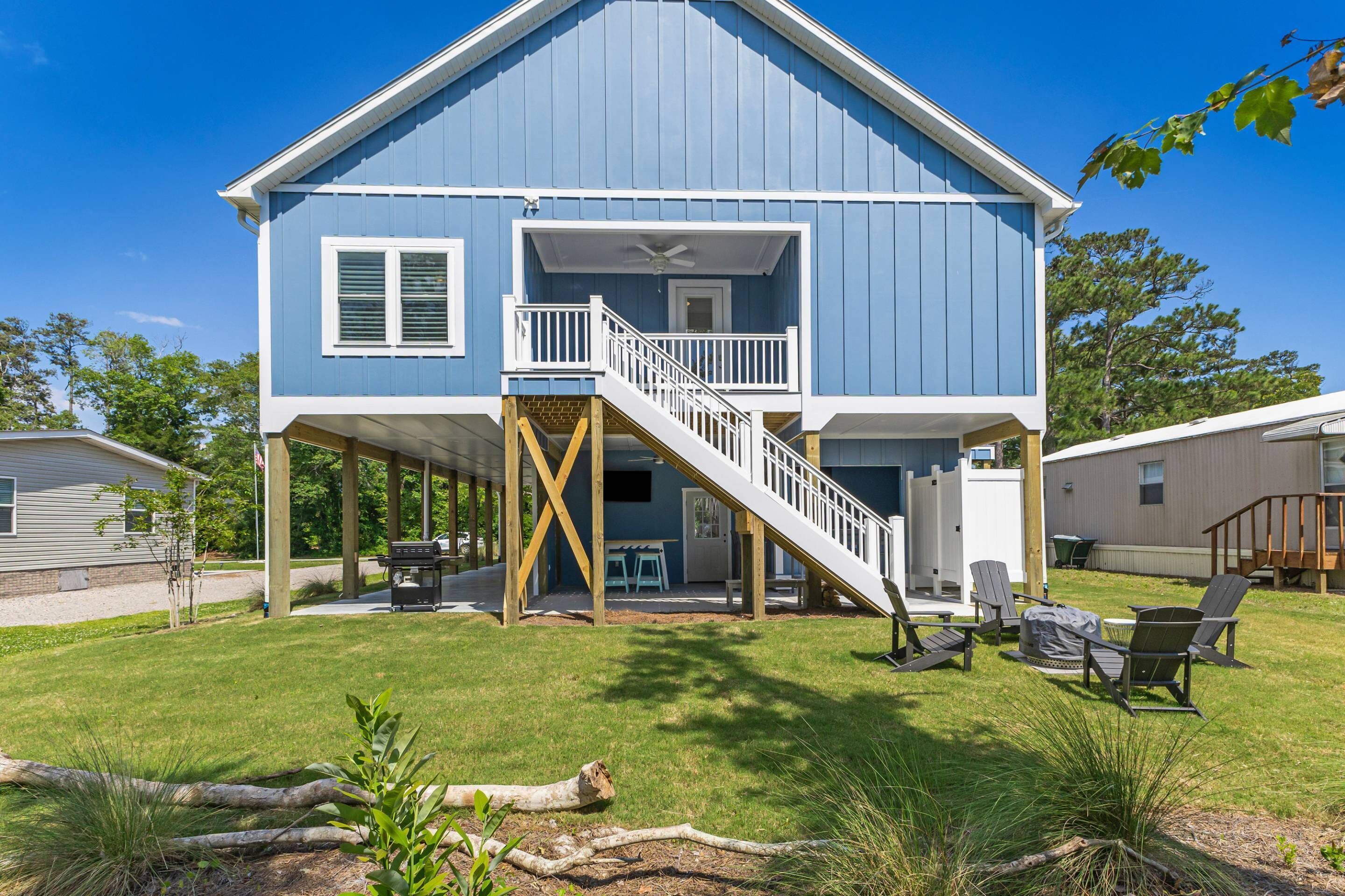 A two-story house with a covered deck, a staircase, outdoor seating, and a grill area.