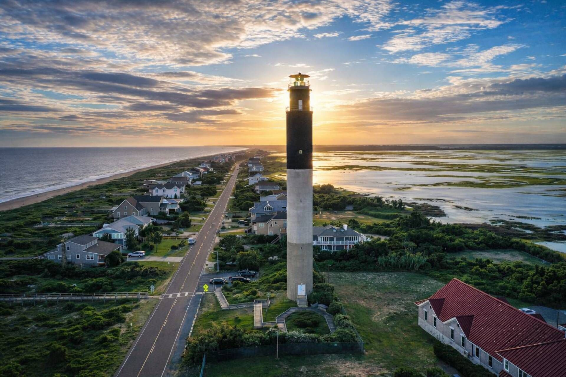 A coastal town with a prominent lighthouse, a main road, and residential houses.