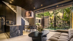 Un interior moderno con cocina, comedor y un ventanal grande con vistas a un jardín.