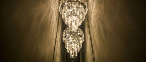 A chandelier in a narrow hallway with a textured wall.