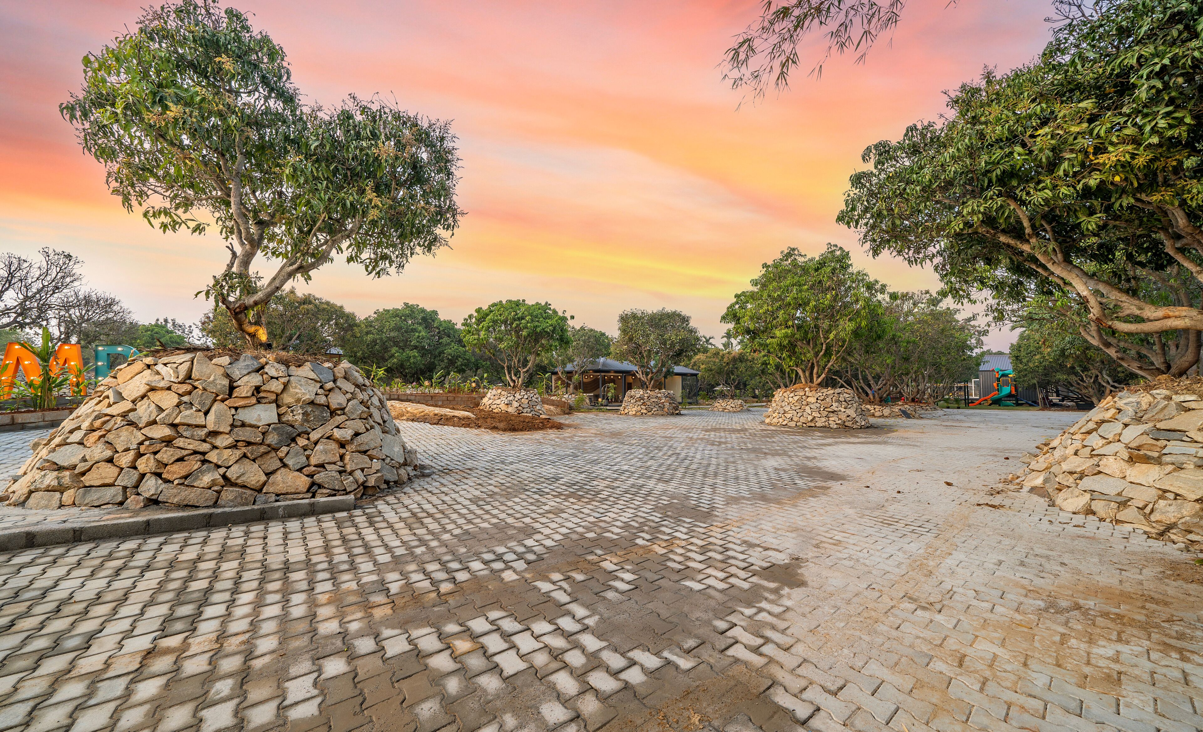 Un espacio pavimentado con estructuras de piedra y árboles, probablemente parte de un parque o jardín.