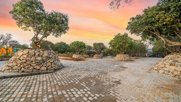 Un espacio pavimentado con estructuras de piedra y árboles, probablemente parte de un parque o jardín.