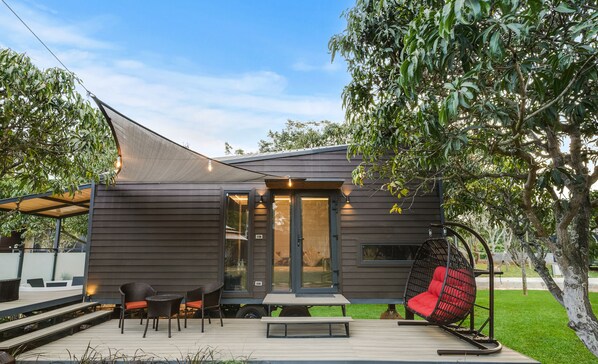 A modern house with a patio, a swing chair, and a dining area.