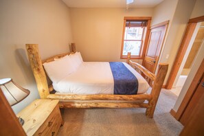 Un cadre de lit en bois, un matelas blanc et une couverture bleue.