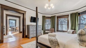 Een slaapkamer met een groot bed, een dressoir, een televisie en uitzicht op de omgeving.
