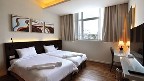 A hotel room with two beds, a desk with a TV, and a window with curtains. - Mio Boutique Hotel Melaka (Malacca City)