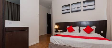A hotel room with a bed, a nightstand, a lamp, and a wall-mounted air conditioner.