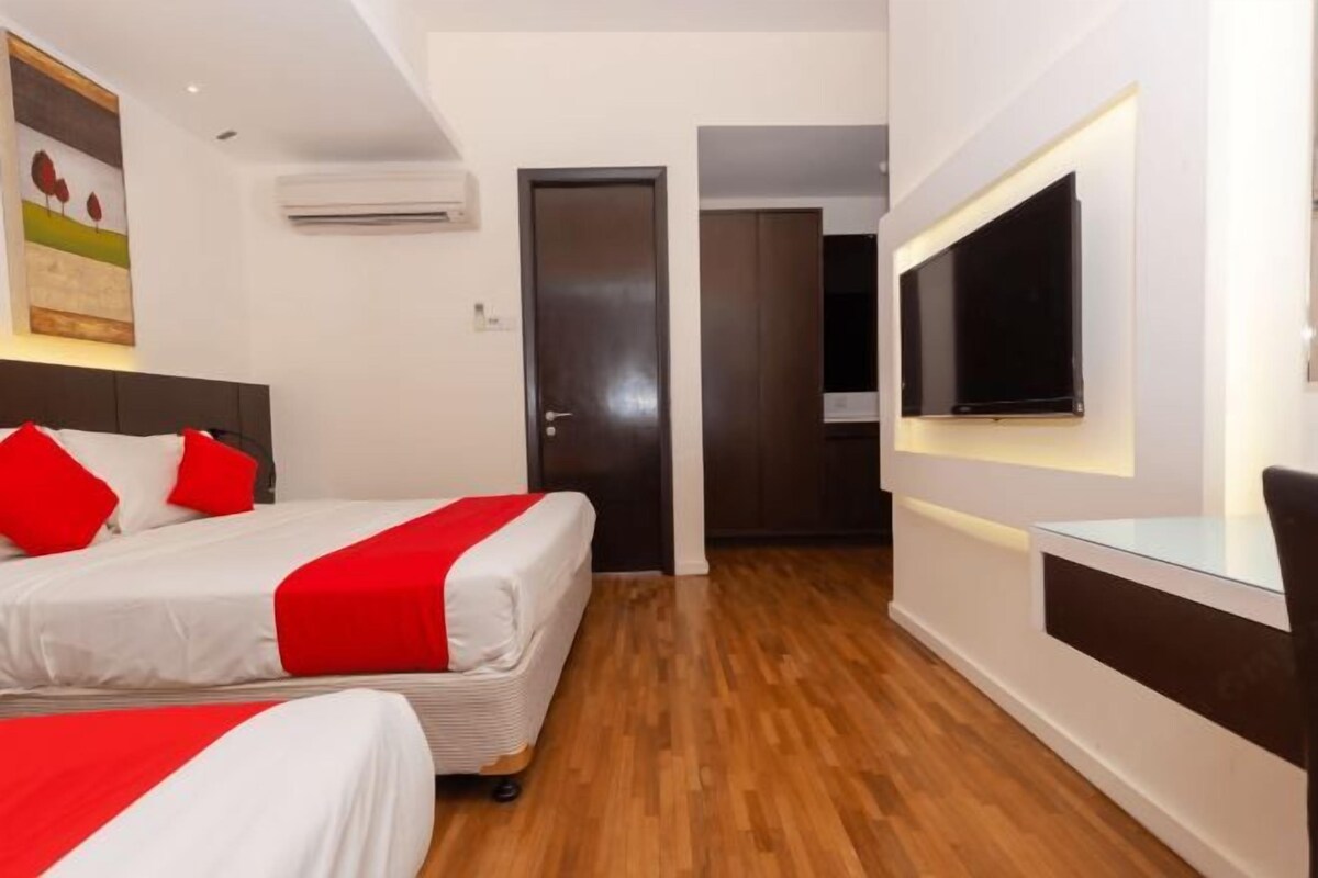 A hotel room with two beds, a TV mounted on the wall, and a wooden floor.