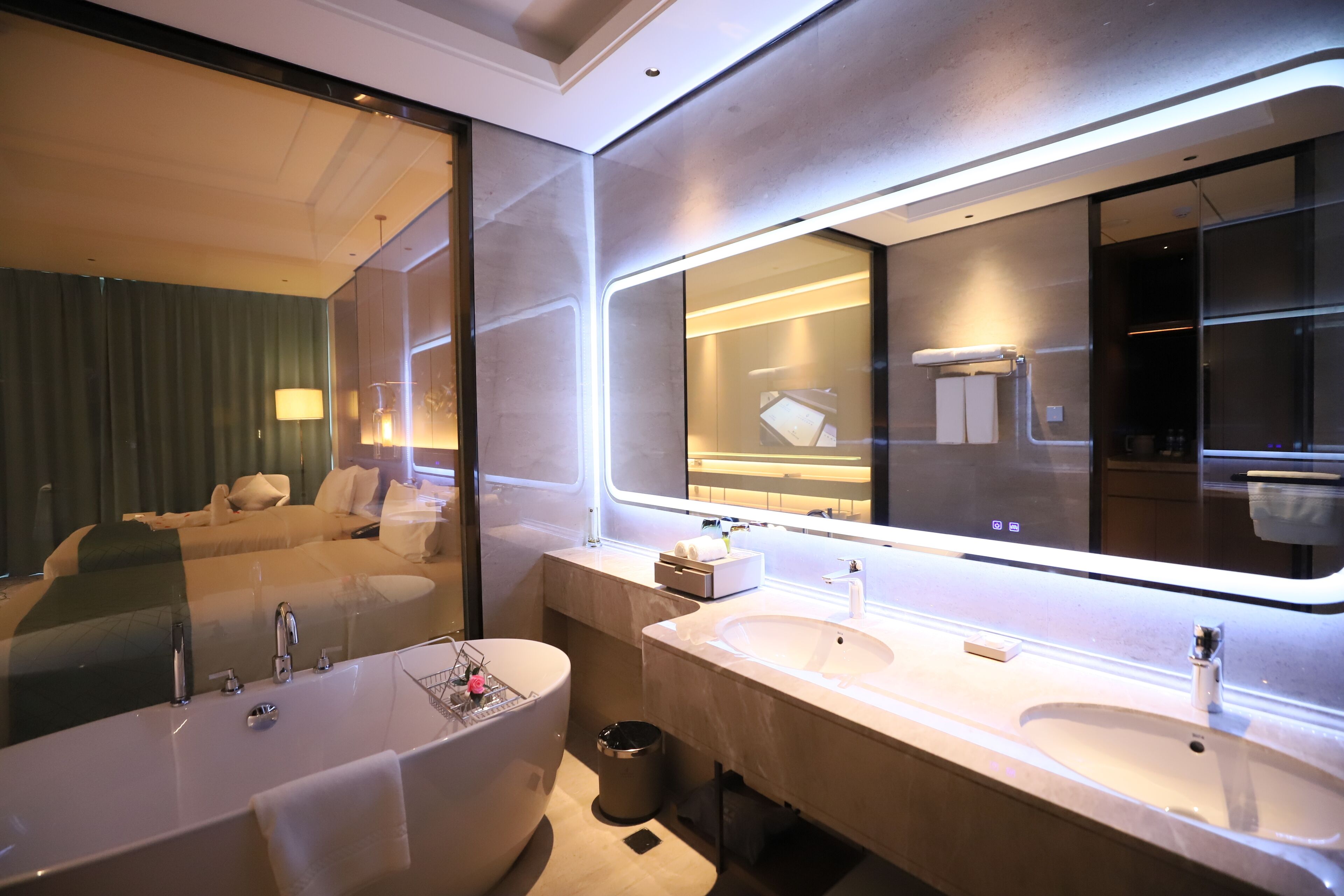 A modern bathroom with a large bathtub, two sinks, and a large mirror.