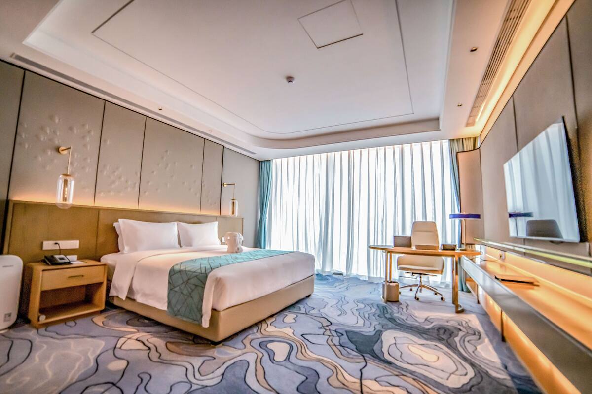 Ein modernes Hotelzimmer mit einem großen Bett, einem Schreibtisch und einem Spiegel.