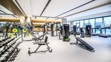 Un gimnasio moderno con diverso equipamiento de ejercicio, amplias ventanas y un diseño limpio y espacioso.