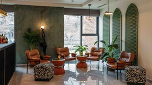 Un espace de détente moderne, avec des fauteuils en cuir, des tables rondes et une grande fenêtre donnant sur la ville.